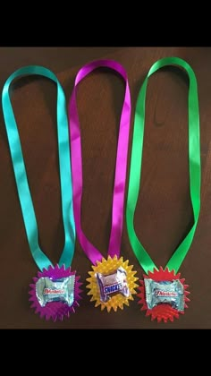 three ribbons with candy bars on them sitting next to each other in front of a wooden table