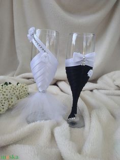 two wine glasses decorated with black and white ribbons, one is made to look like the bride's dress