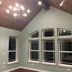 an empty room with three windows and a chandelier