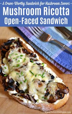 mushroom ricotta open - faced sandwich on a wooden cutting board with fork and napkin