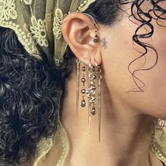 a close up of a person wearing ear rings and earrings with chains attached to them