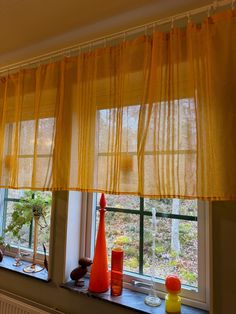 two windows with yellow curtains and vases on the window sill in front of them