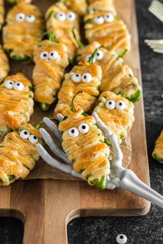 a wooden cutting board topped with food covered in googly eyes and toothpicks