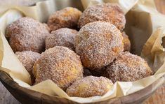 powdered sugar covered donuts in a wooden bowl