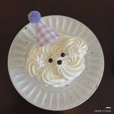 a white plate topped with a cake covered in icing and a purple party hat