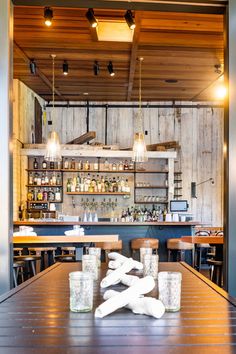 an empty table in a restaurant with bottles and glasses on the table, lights hanging from the ceiling