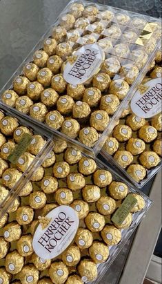 two clear boxes filled with gold foiled chocolates on top of a counter next to each other