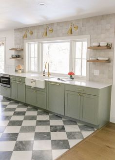 a kitchen with checkered flooring and green cabinets on the wall above the sink