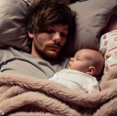 a man laying in bed next to a baby