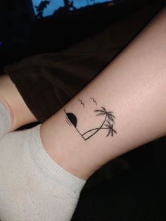 a woman's arm with a tattoo that has a palm tree and birds on it