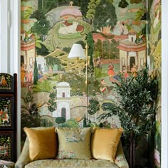 a couch sitting in front of a painting on the wall next to a potted plant