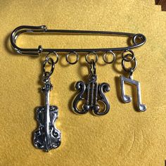 three charms are hanging from a metal hook on a yellow surface with music notes and trefoils