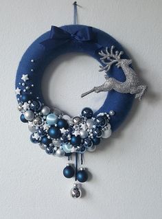 a blue wreath with silver and white ornaments hanging from it's side on a wall