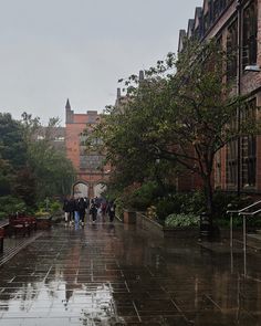 people are walking down the sidewalk in the rain