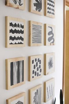 the wall is decorated with many different types of art on wooden frames, including black and white prints