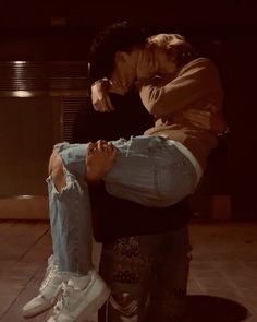 a woman is holding onto the leg of a man in jeans and white sneakers, both with their hands on each other's hips