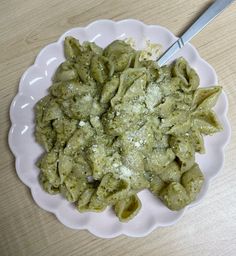 a white plate topped with pasta covered in pesto