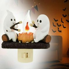 two ghost figurines roasting marshmallows over a campfire