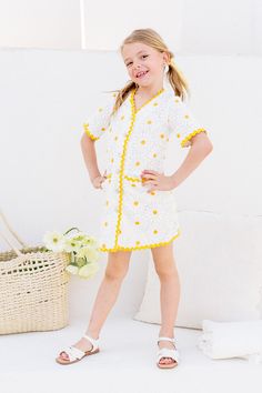 The Mini Delilah Dress will have you feeling like a dainty daisy in no time. With a playful white and yellow crocheted print, this knee-length dress features a V-neckline, contrasting trim, and functional front buttons adorned with pearls and rhinestones. Plus, the fully lined non-stretch fabric ensures both style and comfort. Crochet Short Dresses, Girls Holiday Dresses, Crochet Short, White Dress Party, Contrasting Trim, Holiday Party Dresses, Boys Romper, Everyday Dresses, Girls Rompers