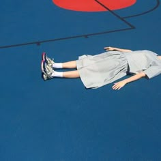 a woman laying on top of a tennis court with a racquet in her hand