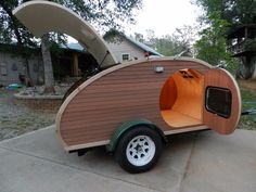 a small wooden trailer with an open door on the front and side doors is parked in a driveway