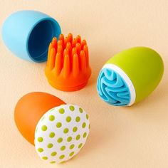 three different colored toothbrushes sitting next to each other on a beige surface with polka dots