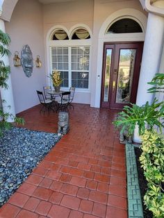 a patio with chairs, table and potted plants in front of the door way