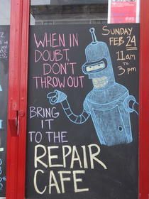 a chalkboard sign with the words repair cafe written on it and an image of a robot holding a screwdriver