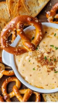 a bowl filled with dip surrounded by pretzels and crackers on the side