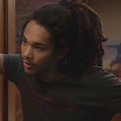 a young man with dreadlocks looking out the window