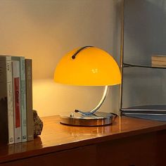 a yellow lamp sitting on top of a wooden table next to a bookshelf