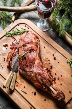 a large piece of meat sitting on top of a cutting board next to a glass of wine