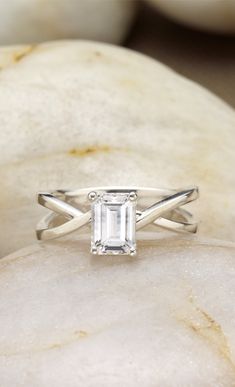 a white diamond ring sitting on top of a rock