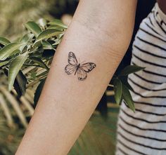 a woman's arm with a small butterfly tattoo on the left side of her arm