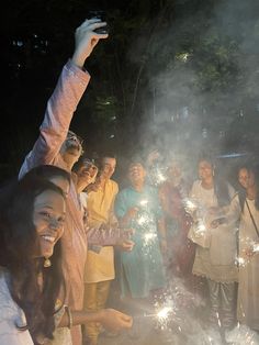 a group of people standing next to each other holding sparklers