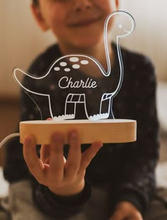 a young boy is holding up a plastic toy dinosaur with the name charlie on it