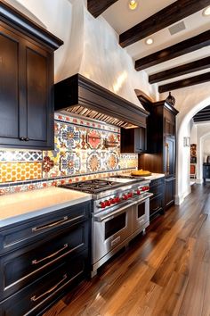 a kitchen with wooden floors and black cabinets, an oven and stove top range in the center