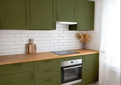 a kitchen with green cabinets and white subway backsplash, wood counter tops, and an oven