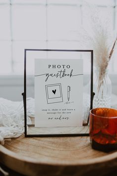 a photo frame sitting on top of a wooden table next to a vase and candle