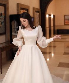 a woman in a white wedding dress standing on a marble floor with her arms outstretched