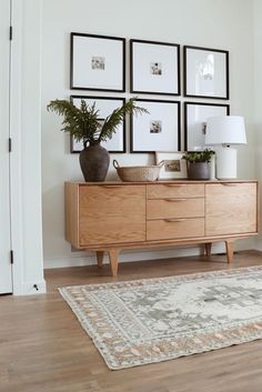 a living room with pictures on the wall and a large rug in front of it