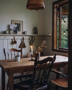 a wooden table with two chairs and a candle on it in front of a window