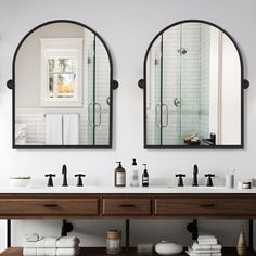 there are two mirrors on the wall above the sinks in this bathroom, one is black and the other is white