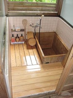 a bathroom with wooden flooring and white tile on the walls, along with an open window