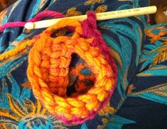 an orange crocheted object with a pencil sticking out of it