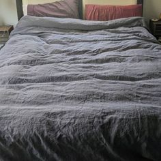 an unmade bed with two nightstands in the background