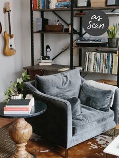 a living room filled with furniture and a guitar on top of a book shelf in front of a bookshelf