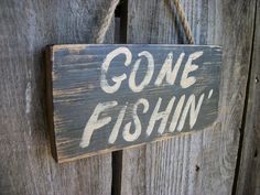 a sign that says gone fishin hanging on a wooden fence with rope attached to it