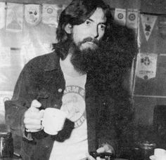 an old photo of a man with long hair and beard standing in front of a counter