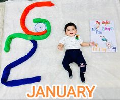 a baby laying on top of a white blanket next to a sign that says january